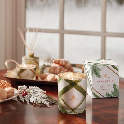 Thymes Frasier Fir Frosted Plaid Votive Candle is a Christmas Candle being lit on kitchen table